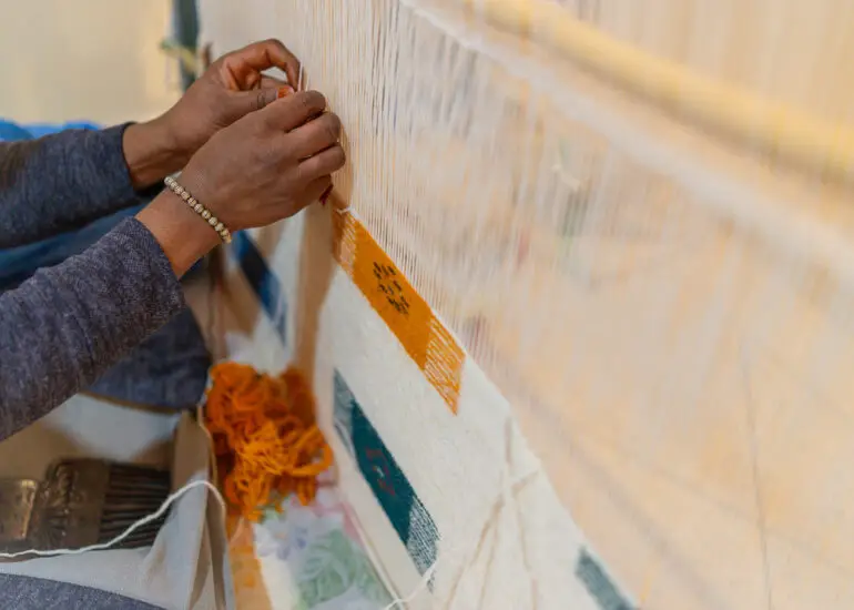An Amazigh woman weaving a rug on a traditional vertical loom in Taznakht