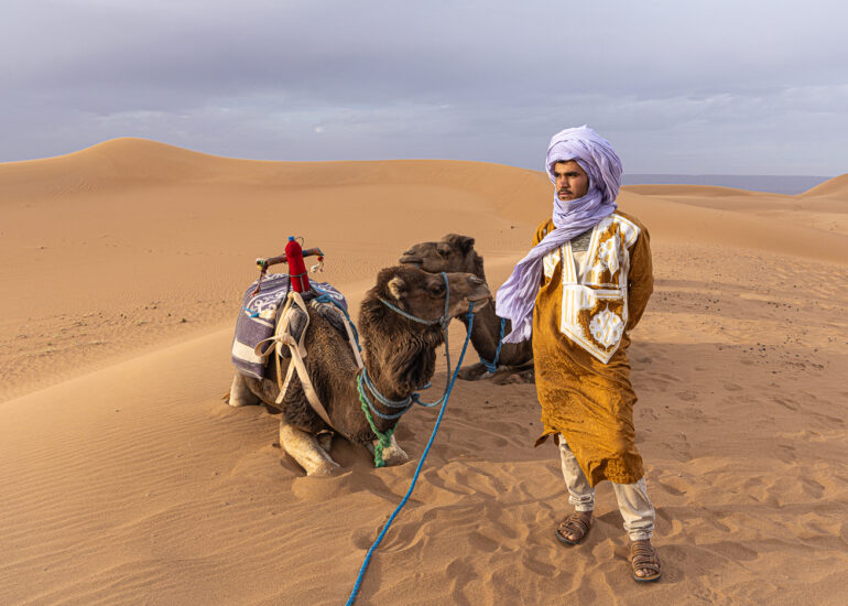 An Amazigh camel herder with his camel in the Erg Chigaga Desert
