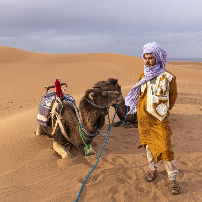 An Amazigh camel herder with his camel in the Erg Chigaga Desert
