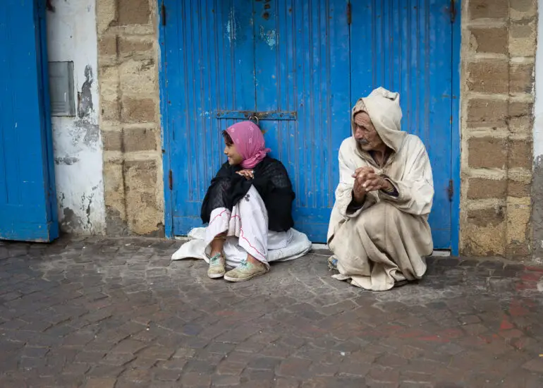 An older man and young girl sitting in a blue doorway