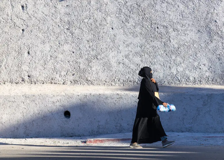 A woman walking along the wall surrounding Taroudant