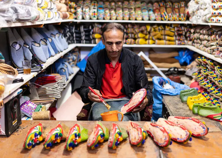 A slipper craftsman painting traditional shoes